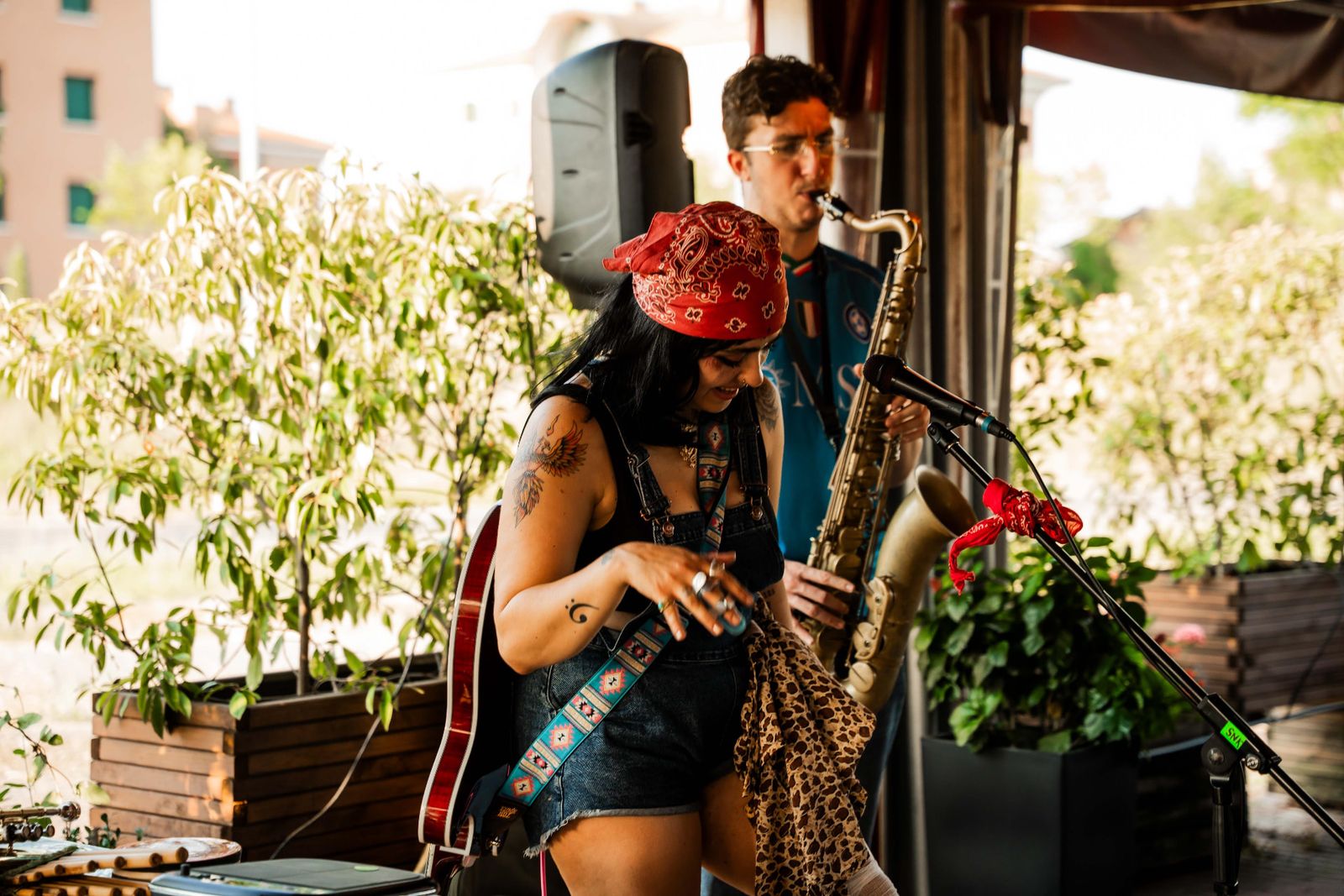 MALAKIIA suona la chitarra dal vivo mentre un sassofonista accompagna